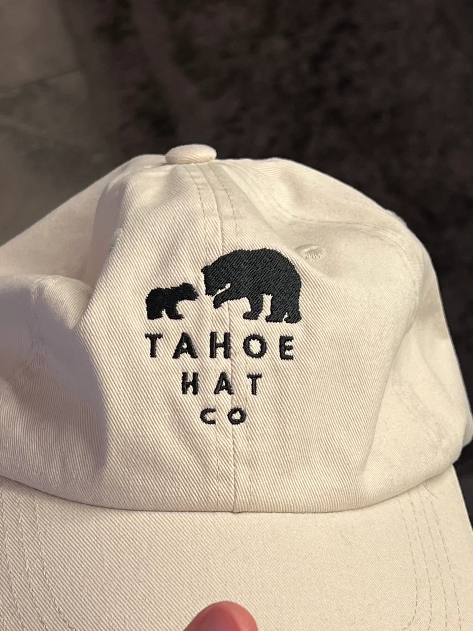 Close view of the black bear and cub stitching on a cream cap